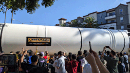 A crowd of onlookers watches as one of Endeavour's two solid rocket motors enters the premises at Exposition Park in Los Angeles...on October 11, 2023.