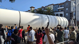 The crowd of onlookers watches as one of Endeavour's two solid rocket motors enters the premises at Exposition Park in Los Angeles...on October 11, 2023.