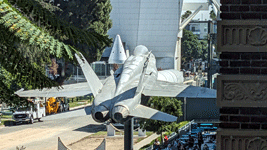 A nose cone for one of Endeavour's two solid rocket boosters is visible above the F/A-18 Hornet on display near the Rose Garden at Exposition Park in Los Angeles...on October 11, 2023.