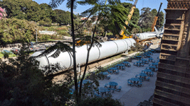 The second of Endeavour's two solid rocket motors (near the F/A-18 Hornet) is about to be lifted and placed onto a temporary workstand near the Rose Garden at Exposition Park in Los Angeles...on October 11, 2023.