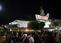 Space shuttle Endeavour dwarfs a Krispy Kreme Doughnuts sign near the Baldwin Hills Crenshaw Plaza, on October 13, 2012.