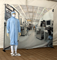 The mannequin posing in front of a large image of a laboratory.