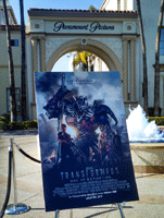 A film poster for TRANSFORMERS: AGE OF EXTINCTION on display near the Bumblebee movie prop at Paramount Studios