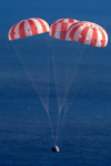 With its three main parachutes deployed, the Orion spacecraft is about to splash down into the Pacific Ocean to conclude the EFT-1 mission, on December 5, 2014