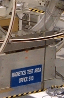 Two technicians at work within the Spacecraft Assembly Facility.  Behind them is a mannequin dressed in a blue clean suit.