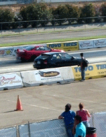 A crowd watches two import cars drag race