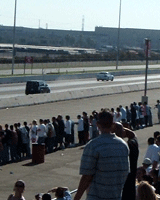 A crowd watches two import cars drag race