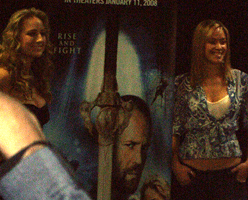 KRISTANNA LOKEN and LEELEE SOBIESKI pose next to a poster for the film IN THE NAME OF THE KING: A DUNGEON SIEGE TALE